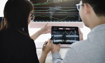 An investment expert points a pen at a tablet monitor to analyze the stock market to teach you how to make a profit.