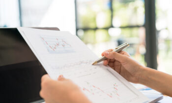 Business woman hand with Financial charts and laptop on the tabl