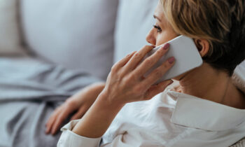 Pensive woman talking on the phone while relaxing on the sofa at