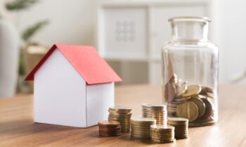 miniaturbank-mit-munzstapeln-und-glas-daneben