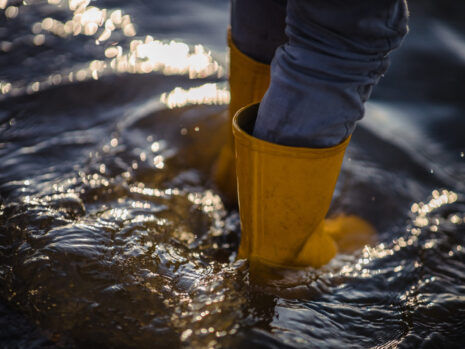 person in blue denim jeans and yellow boots standing on water