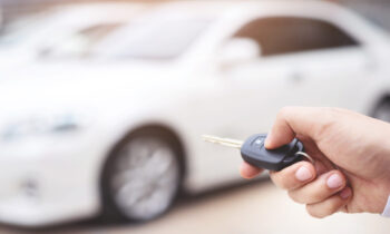 The salesman is opening and closing the car door with the key. F